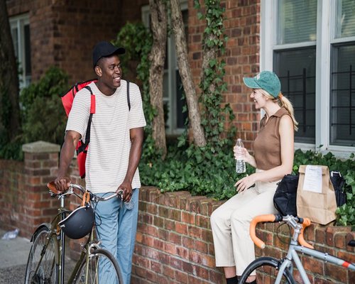 Two cyclists chatting outside a small local coffee shop with their bikes parked nearby